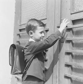Chłopiec otwierający drzwi do szkoły